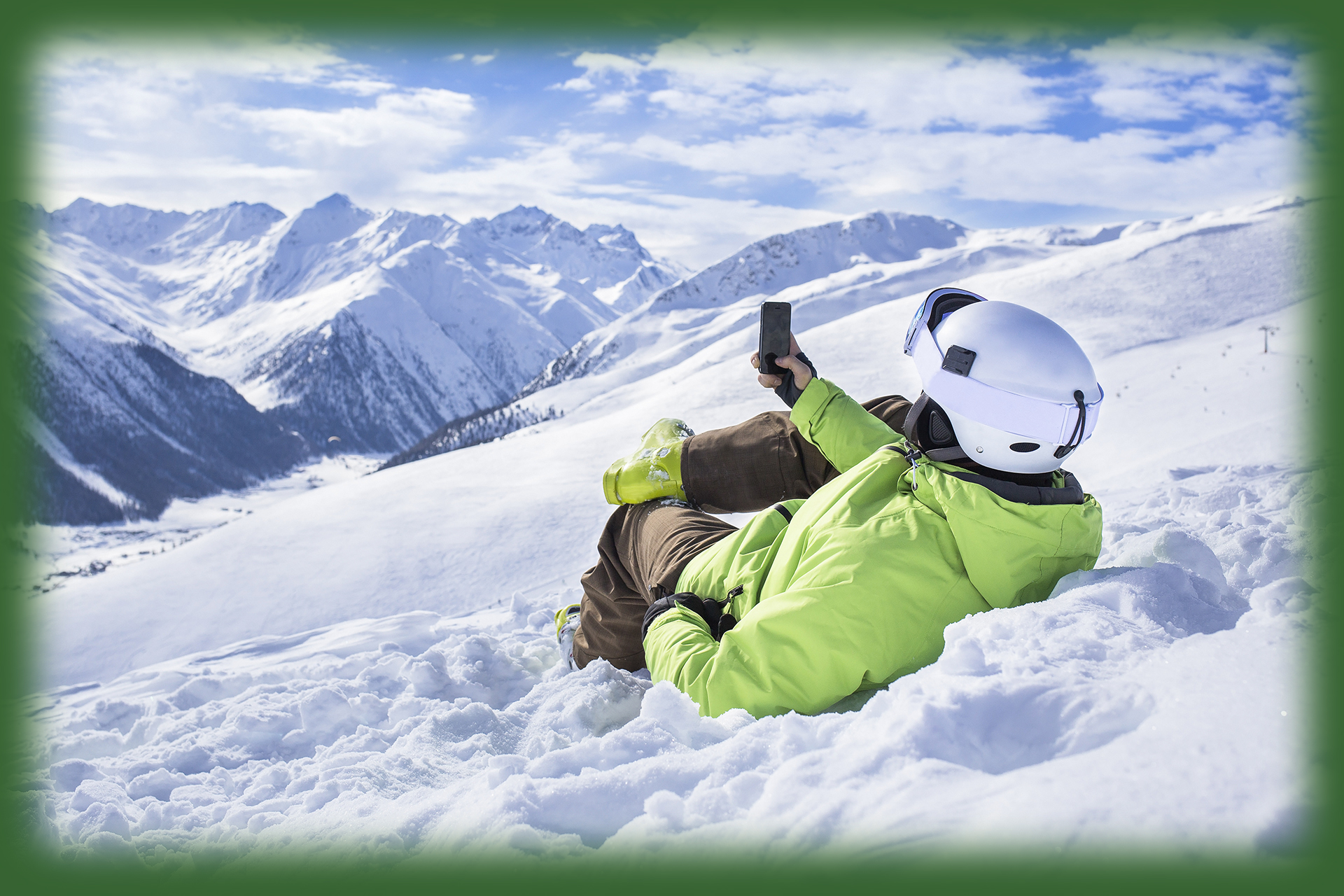 man laying in snow viewing a cell phone